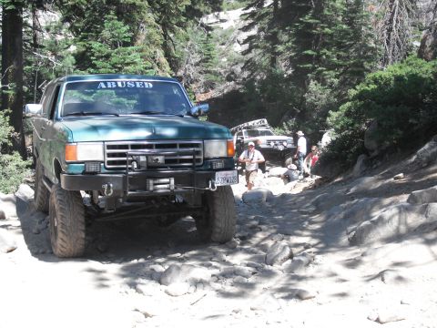 1991 Ford Bronco - A 1991 Ford Bronco navigates a challenging rocky trail, with another off-road vehicle following closely.