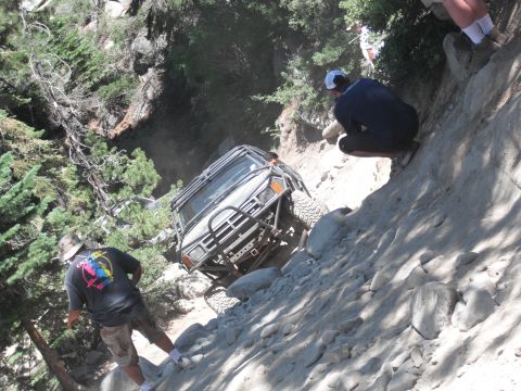 1991 Ford Bronco - An off-road vehicle navigates a steep, rocky trail with onlookers observing.