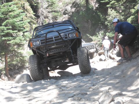 1991 Ford Bronco - Off-road Toyota truck navigating a difficult rocky terrain with another vehicle following.