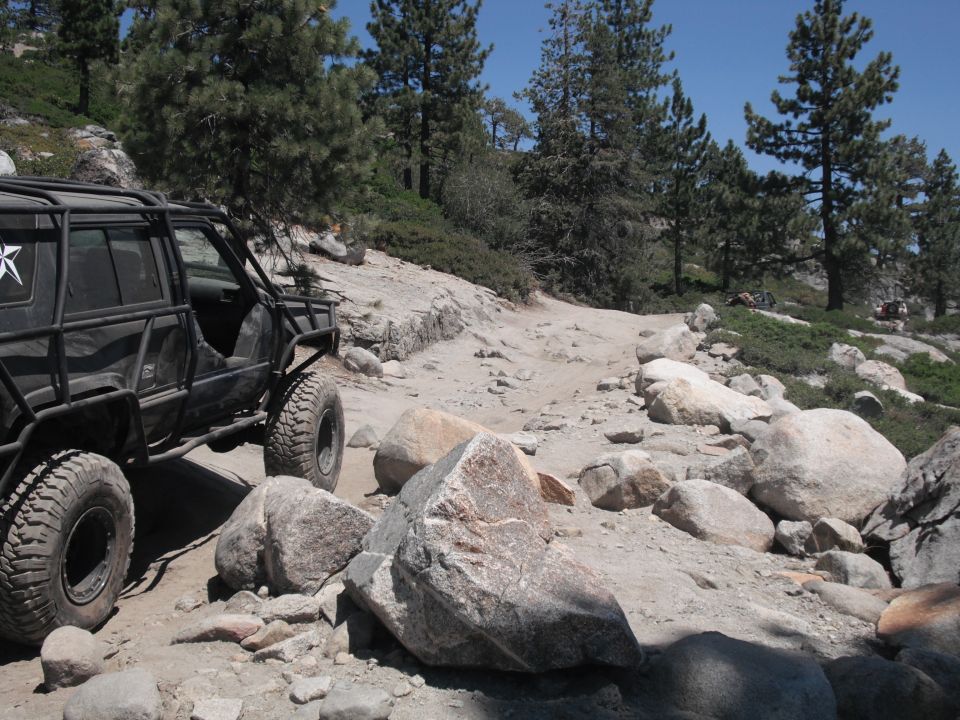 Black off-road vehicle with external roll cage on rocky terrain