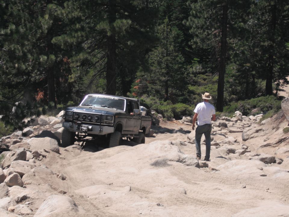 Ford F-Series pickup truck on rocky trail, man walking behind it