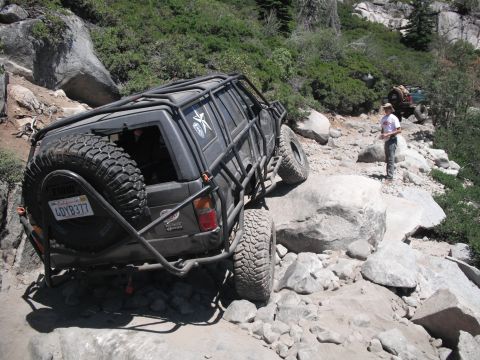 1991 Ford Bronco - Modified 1991 Ford Bronco navigates a challenging rocky trail, with another vehicle visible in the background.
