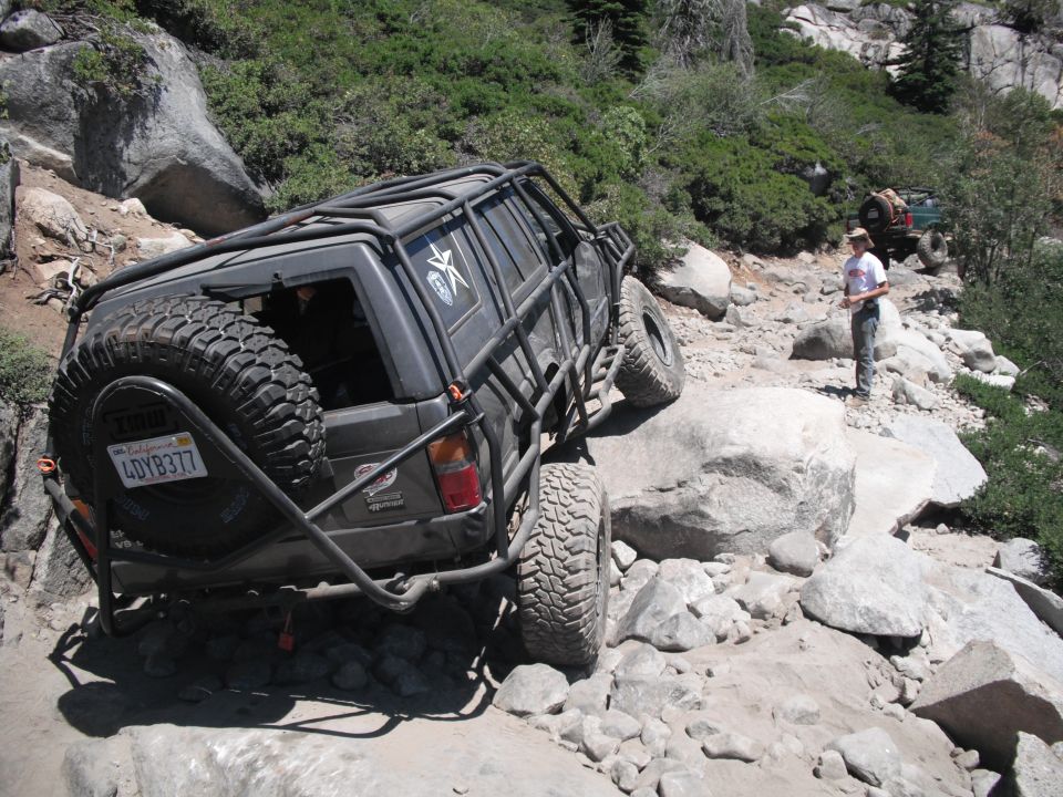 1991 Ford Bronco modified for off-roading on a rocky trail with a spare tire mounted on the rear