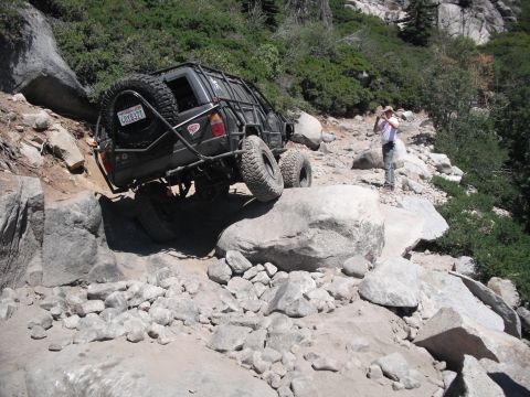 1991 Ford Bronco - Off-road vehicle carefully maneuvers over large rocks on a steep, trail.