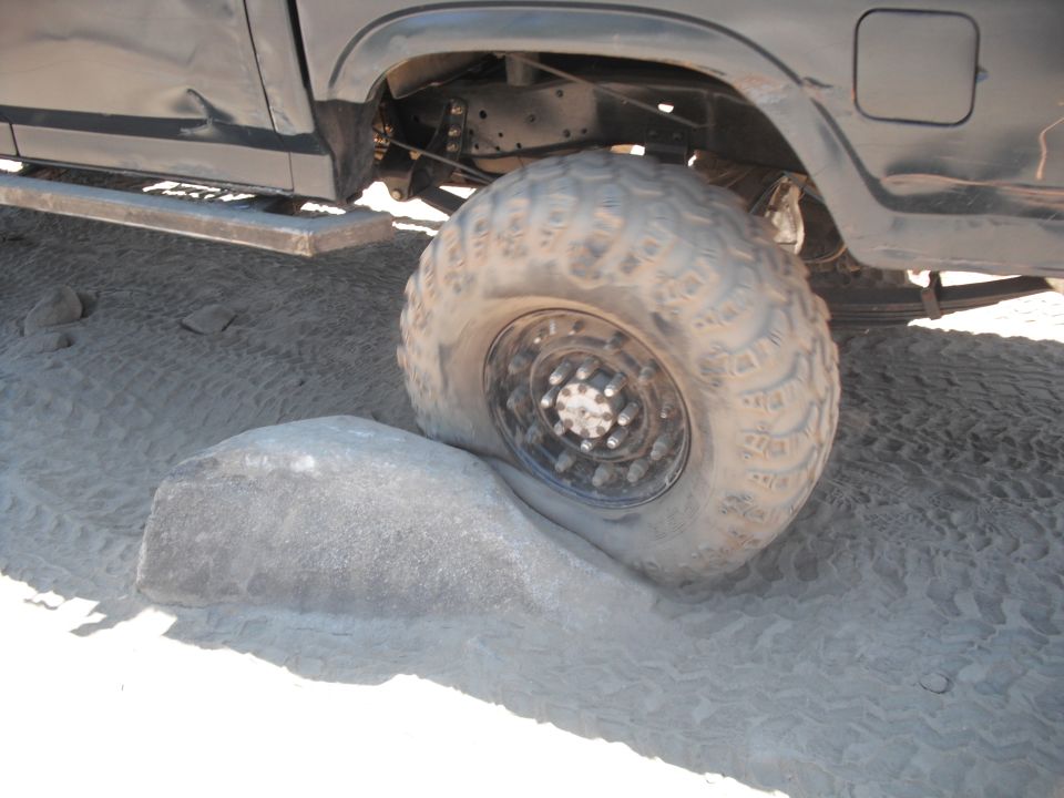 Big off-road tire wedged on a rock in sand