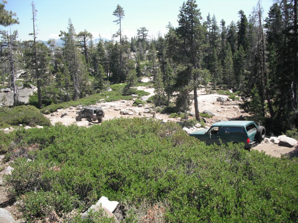 Green SUV with spare tire on rear, parked on rocky terrain