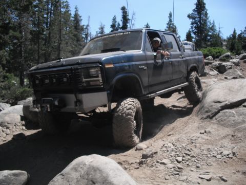 1991 Ford Bronco - This pickup truck is shown off-roading on a challenging rocky path, demonstrating its capabilities.