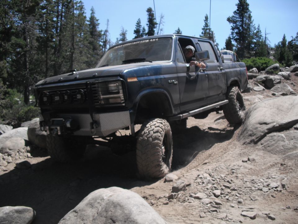 Dark blue pickup truck with large tires navigating rocky terrain