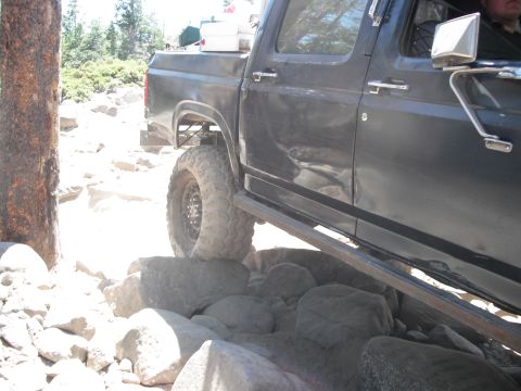 1991 Ford Bronco - This truck is navigating a rocky trail, with its tires positioned on large boulders.