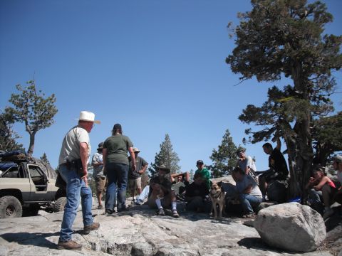 1991 Ford Bronco - A group of people and an off-road vehicle are gathered on a rocky landscape under a clear blue sky.