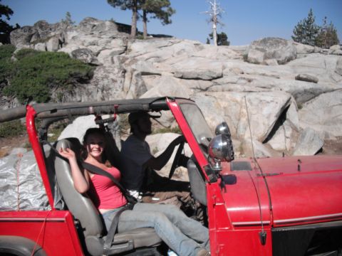 1991 Ford Bronco - Two people enjoy a ride in a red Jeep Wrangler through a rocky, mountainous landscape.