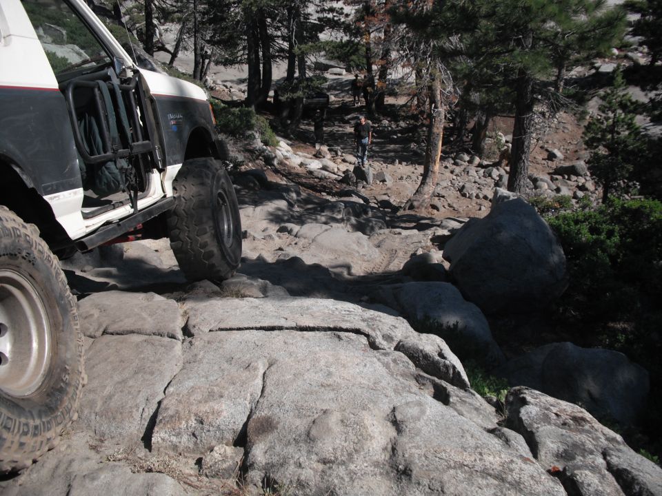 1991 Ford Bronco navigating a rocky trail with trees and boulders