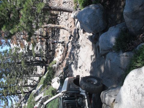 1991 Ford Bronco - This 1991 Ford Bronco is tackling a challenging off-road path with significant rock obstacles.