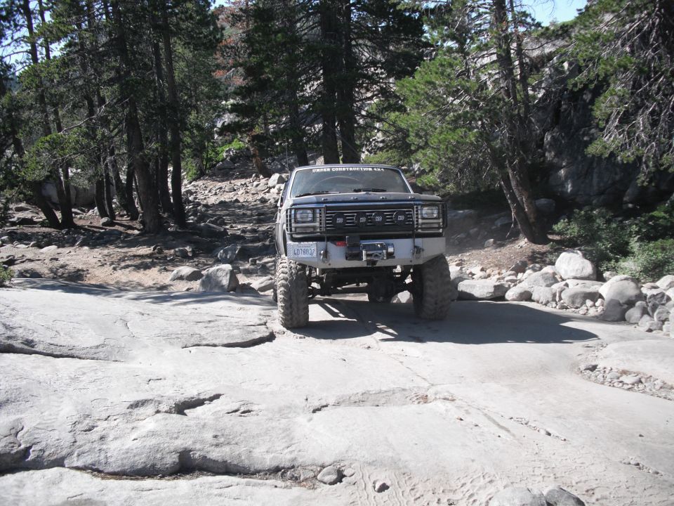 Modified Ford Bronco with large tires and winch on rocky terrain
