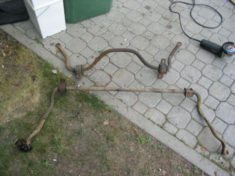 1986 Ford Bronco - Two old sway bars are shown on the ground with a power tool nearby.