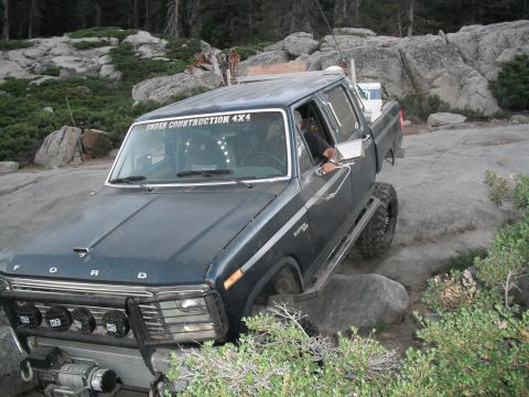 1991 Ford Bronco - This modified pickup truck navigates a rocky trail, with "UNDER CONSTRUCTION 4X4" visible on the windshield.