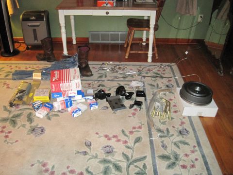1979 Ford Bronco - Various vehicle parts are spread across a rug, including a brake drum and hardware, with a desk and chair in the background.