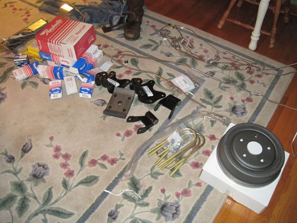 Vehicle suspension parts including U-bolts and brackets, plus a brake drum and boxes of Raybestos parts