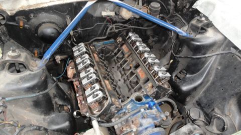 1964 Ford Fairlane - The engine bay of a vehicle is shown with a V8 engine and a blue strut tower brace.