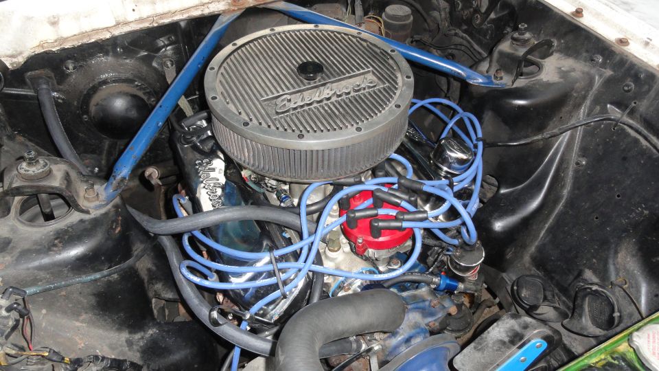 V8 engine bay with Edelbrock air cleaner, blue plug wires, red distributor cap