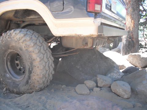 1991 Ford Bronco - The rear tire and undercarriage of a 1991 Ford Bronco navigate a rocky trail.