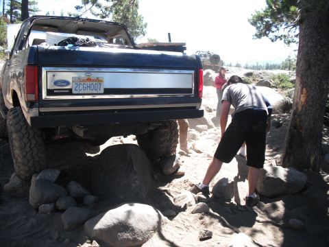 1991 Ford Bronco - Ford Bronco navigating difficult terrain with assistance from bystanders.