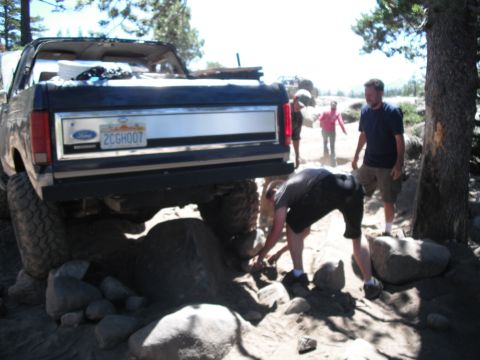 1991 Ford Bronco - A Ford Bronco is being carefully driven over rocks by off-road enthusiasts on a sunny day.