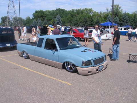 2001 Chevrolet Silverado 1500 - A custom pickup truck with a two-tone paint scheme and significantly lowered suspension is parked at an outdoor event.