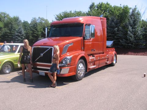2001 Chevrolet Silverado 1500 - Orange semi-truck with Volvo branding is parked next to a vintage car.