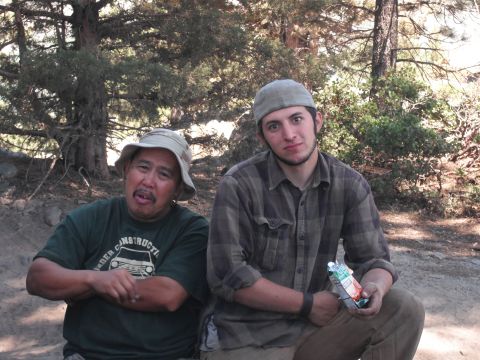 1991 Ford Bronco - Two men are sitting outdoors in a wooded area, one wearing a bucket hat and the other a baseball cap.