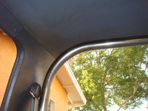 1992 Ford Bronco - The photo shows the interior of a vehicle, focusing on a roll cage and seatbelt, with a view of the outdoors.