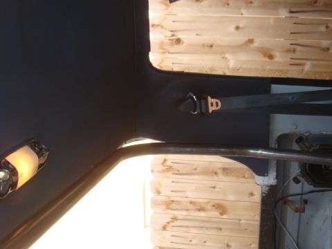 1992 Ford Bronco - Interior view of a vehicle showing a roll cage and seatbelt against wood-paneled walls.