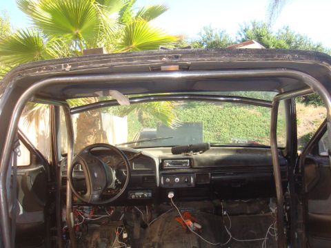 1992 Ford Bronco - The interior of a truck is shown, a roll cage and exposed wiring.