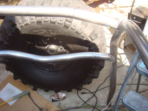 1992 Ford Bronco - A close-up view of a roll cage being installed around a large tire, with tools and debris scattered nearby.