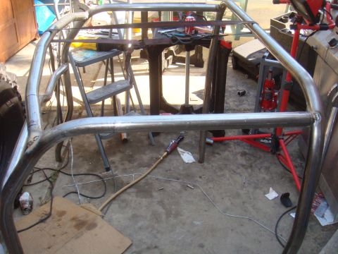 1992 Ford Bronco - A custom metal roll cage is under construction, with various tools and equipment scattered around the workspace.