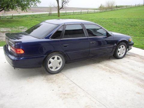 1993 Ford Taurus - This 1993 Ford Taurus sedan is shown from the side, a subtle rear spoiler and distinctive five-spoke wheels.