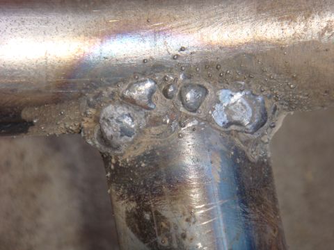 1992 Ford Bronco - Close-up view of poorly executed welds on metal tubing, showing significant porosity and slag.