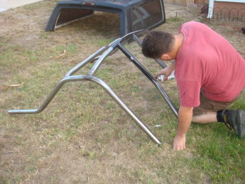 1992 Ford Bronco - Custom roll cage being painted outdoors. Truck bed cap visible in background.