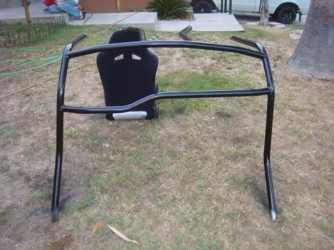 1992 Ford Bronco - A black roll cage and racing seat are displayed outdoors on a grassy area.