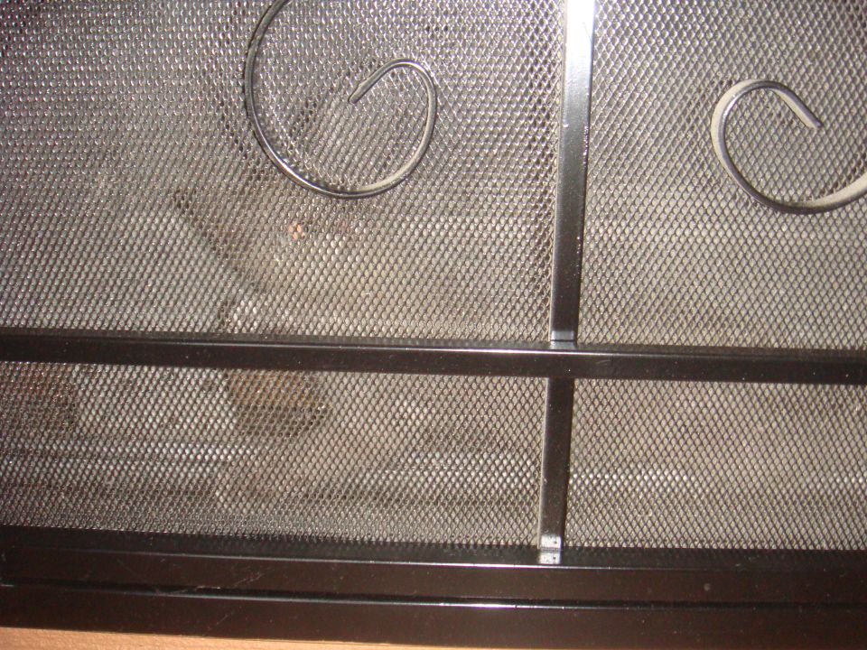 Black metal fireplace screen with decorative scrollwork and mesh