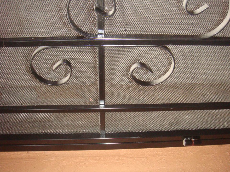 close-up of a decorative metal screen with scrollwork over mesh