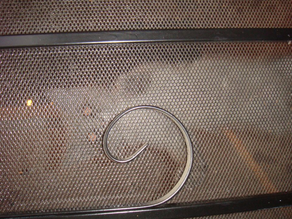 Close-up of a metal mesh screen with a curved metal trim piece on it. Supermotors.net logo visible