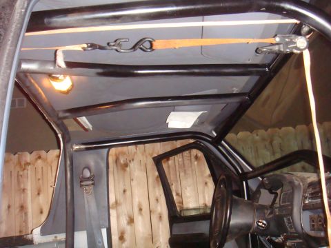 1992 Ford Bronco - Custom roll cage installed inside a vehicle's interior, with a strap secured to the roof.