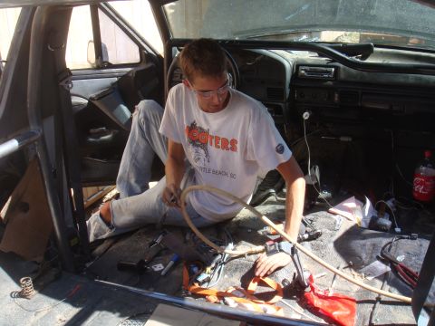 1992 Ford Bronco - Man working on wiring inside a 1992 Ford Bronco with a roll cage.