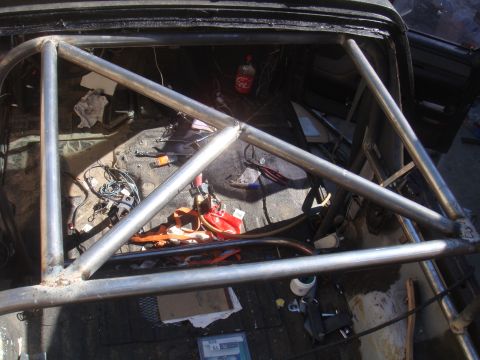 1992 Ford Bronco - A custom roll cage is installed inside a vehicle, with various tools and a soda bottle scattered around the interior.
