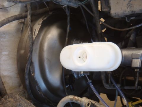 1992 Ford Bronco - Close-up view of a vehicle's brake fluid reservoir and master cylinder, showing the white plastic reservoir.