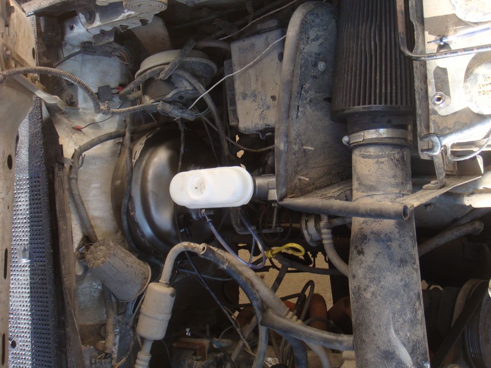 Engine bay showing brake booster, master cylinder, air filter, and various hoses and wires