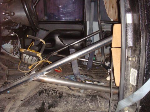 1992 Ford Bronco - The interior of a vehicle is shown, modified with a roll cage and other safety equipment.