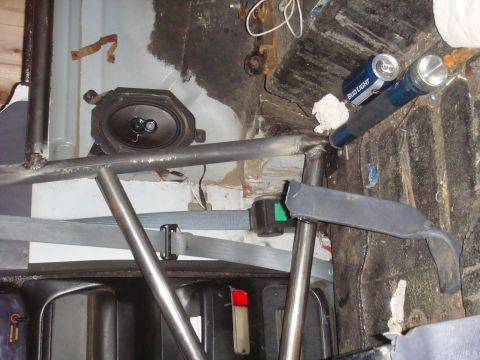 1992 Ford Bronco - The interior of a vehicle shows a roll cage, speaker, and seatbelt, with a can of Bud Light visible.