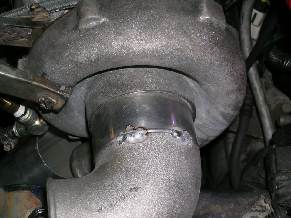 Close-up of turbocharger piping with visible welds and a metal clamp